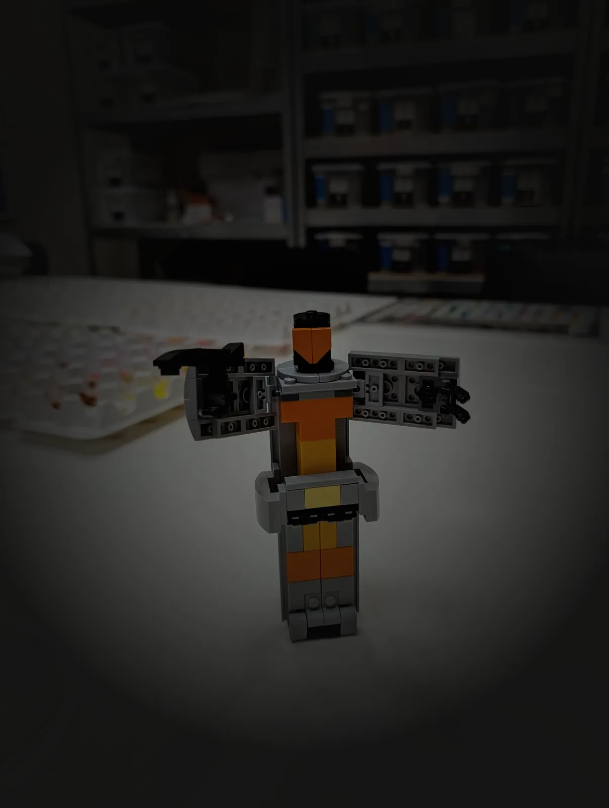 A hand-built prototype standing on the studio workbench for review, trays of sorted elements and parts shelves behind.